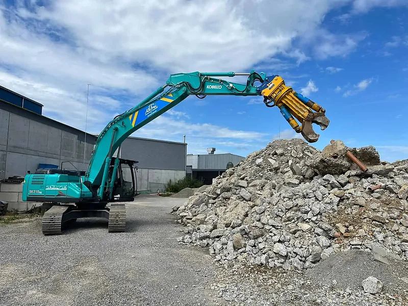 Kobelco-Abbruchbagger mit Sortiergreifer auf einem Betonabbruch-Haufen