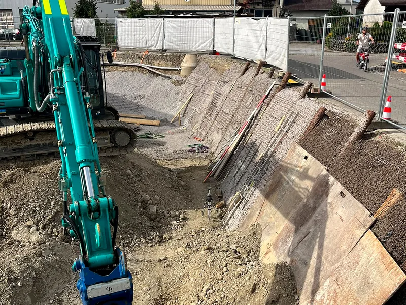 Bagger in einer Baugrube mit gesicherter Böschung