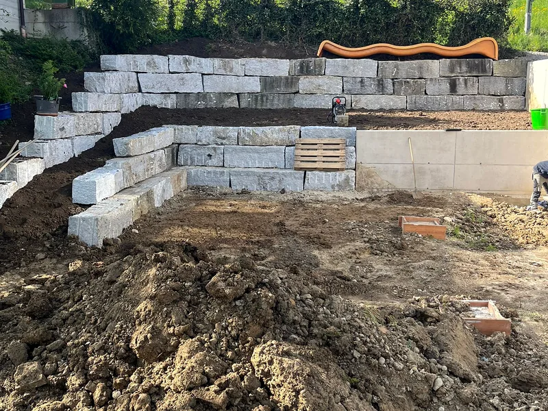 Mit dem Bagger versetzte Blocksteinmauer im Garten