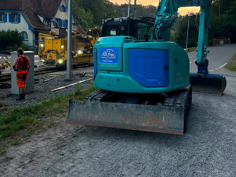 Kompaktbagger Kobelco SK75 bei Gleisarbeiten am Abend